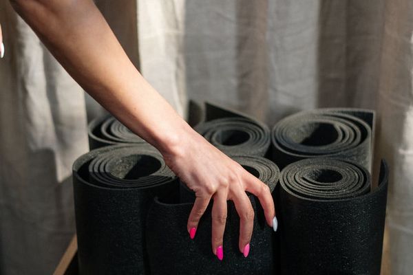 A person rolling out a yoga mat in a bright, welcoming studio.
